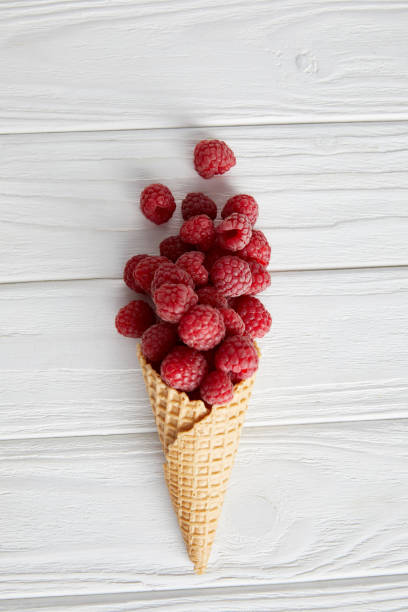istock top view of waffle cone with raspberries on wooden table 1002740876
