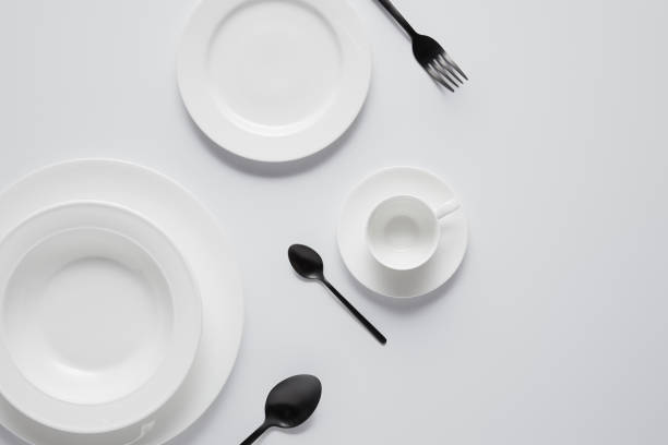 istock top view of various plates, cup, black spoons and fork on white table 1002741006