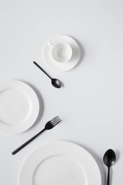 istock top view of plates, cup, fork and black spoons on white table 1002741008