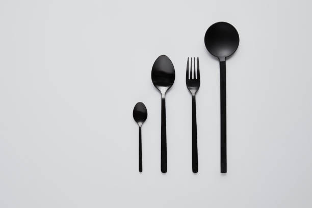 istock top view of black various spoons, fork and salad spoon on white table, minimalistic concept 1002741024