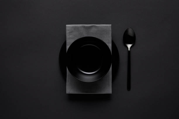 istock top view of black bowl, spoon, kitchen towel and plate on black table, minimalistic concept 1002741070
