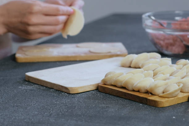 istock Woman makes dumplings with mince meat, close-up hands. 1002746196