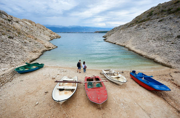 мужчина и женщина с рюкзаками, держась за руки, стоя у кромки воды - hiking coastline waters edge sunny стоковые фото и изображения