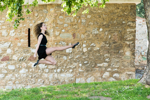 Girl playing Irish dance and jumping in the field.