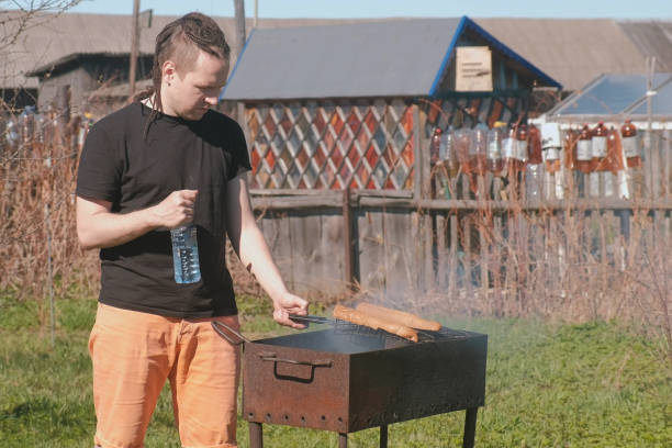 Young man roasting beef cutlets with bread on the grill.
