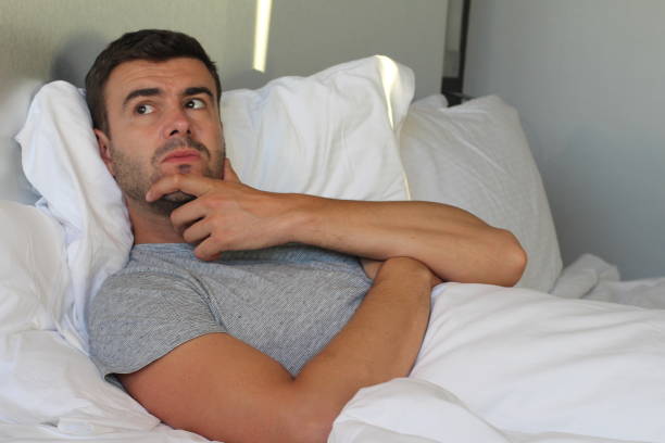 Worried man overthinking in bed Worried man overthinking in bed. erection stock pictures, royalty-free photos & images