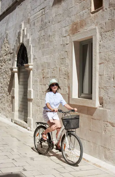 Photo of Young woman riding city bicycle near sea