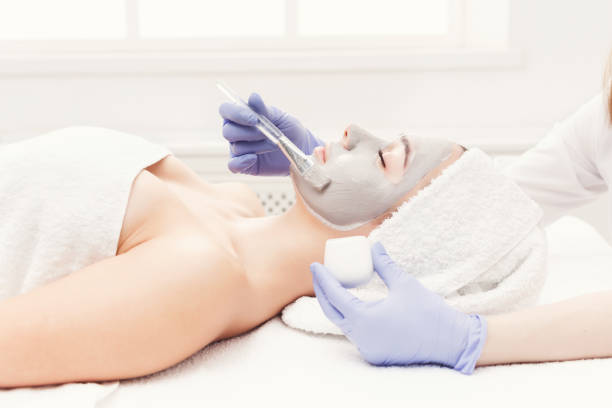 istock Woman gets face mask by beautician at spa 1002756580