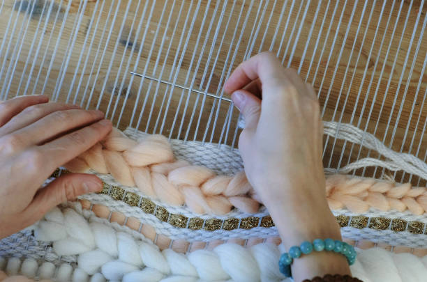 tissage sur un métier à tisser. tissage sur un métier à tisser. mains de closeup femme en cours d’exécution sur un métier à tisser. enfilage de l’aiguille à travers les fils de trame. - tisserin photos et images de collection