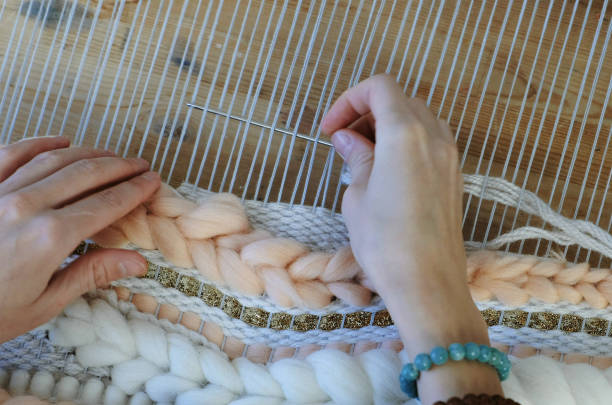 weaving on a loom. weaving on a loom. closeup woman's hands running on a loom. threading the needle through the strands of frame. - weave imagens e fotografias de stock
