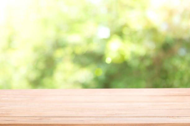istock Blank wood table top with sun and blur green tree. 1002783538