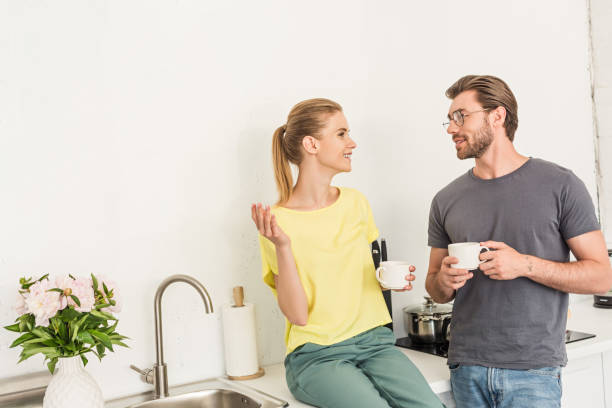 istock happy young couple with coffee cups talking at kitchen 1002792436