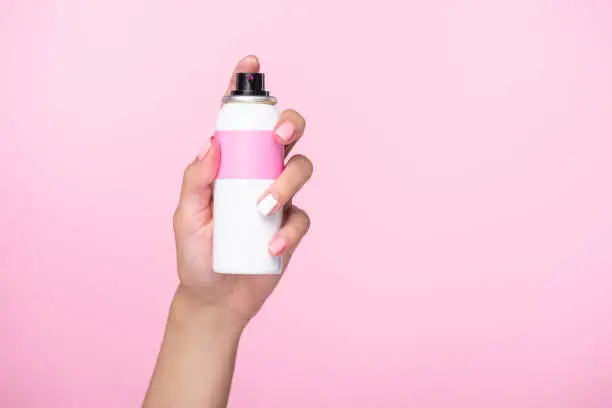 cropped shot of woman holding spray paint for hair isolated on pink