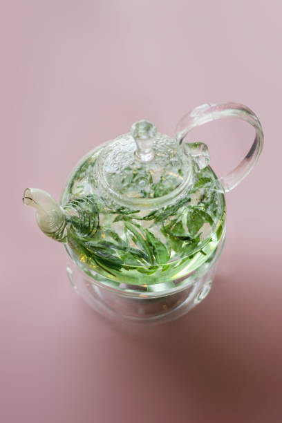 Szklany czajniczek z zieloną herbatą na różowo – zdjęcie