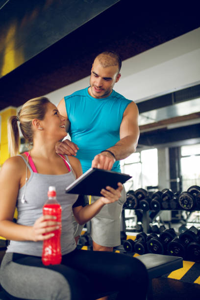 istock Trainer explaining workout regime to young sporty woman 1002793132