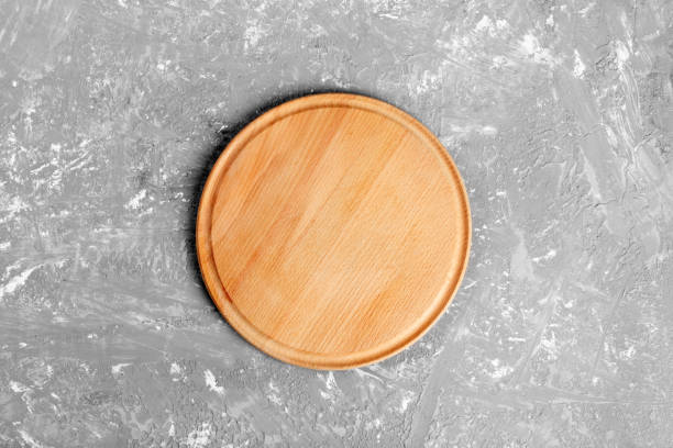 istock Empty round wooden dish on table over gray cement wall background, for product display montage 1002793790