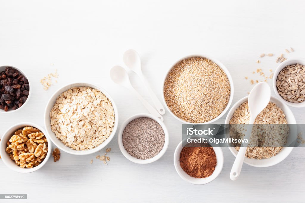 variaty of raw cereals and nuts for breakfast. Oatmeal flakes and steel cut, barley, walnut, chia, raisins. Healthy ingredients Cereal Plant Stock Photo