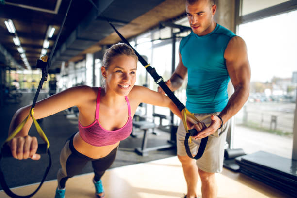 istock Woman doing arm exercises with suspension straps at gym 1002800720