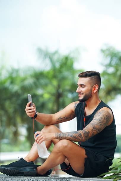 smiling sportsman using phone outdoors - surfing wireless vertical outdoors lifestyles imagens e fotografias de stock