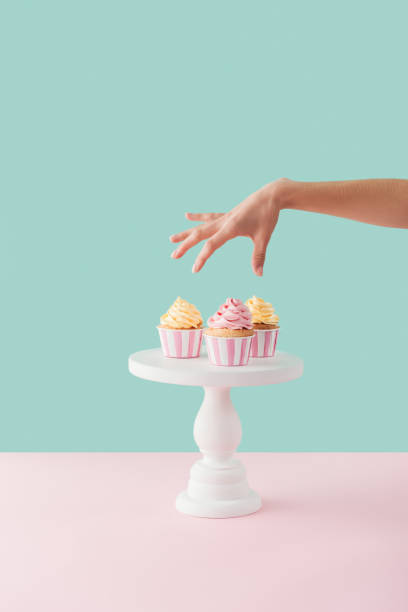 vue recadrée de femme tenant les cupcakes de stand de gâteau - plat à gâteau photos et images de collection