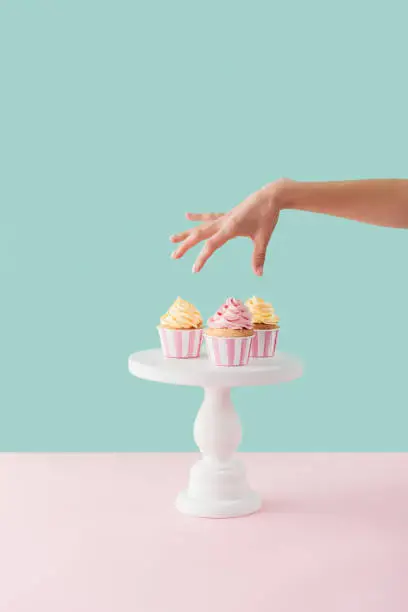 cropped view of woman taking cupcakes from cake stand