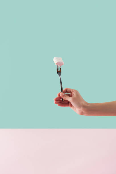 istock cropped view of tattooed hand with sweet marshmallow on fork 1002834800