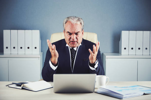 istock Angry elderly businessman talking on video chat 1002847290