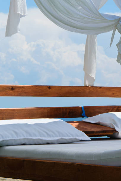 istock Luxury and romantic bed on the seashore for relaxing time (holidays/vacations), white fluffy clouds in the background 1002852704