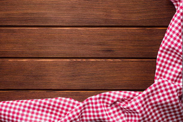 istock Napkin in a red and white cage on a wooden background, texture, 1002859960