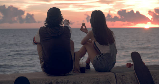 istock Young skater couple watching sunset and talking. 1002862882