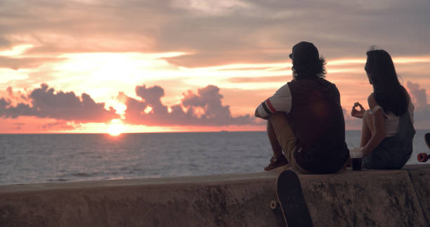 istock Young skater couple watching sunset and talking. 1002862908