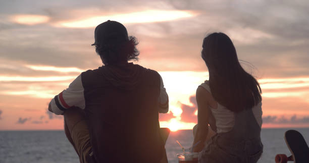 istock Young skater couple watching sunset and talking. 1002862910