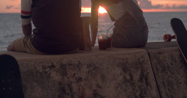 Young skater couple watching sunset and talking.