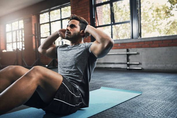 Increasing back, shoulder, and arm strength Shot of a handsome young man working out at the gym sit ups stock pictures, royalty-free photos & images