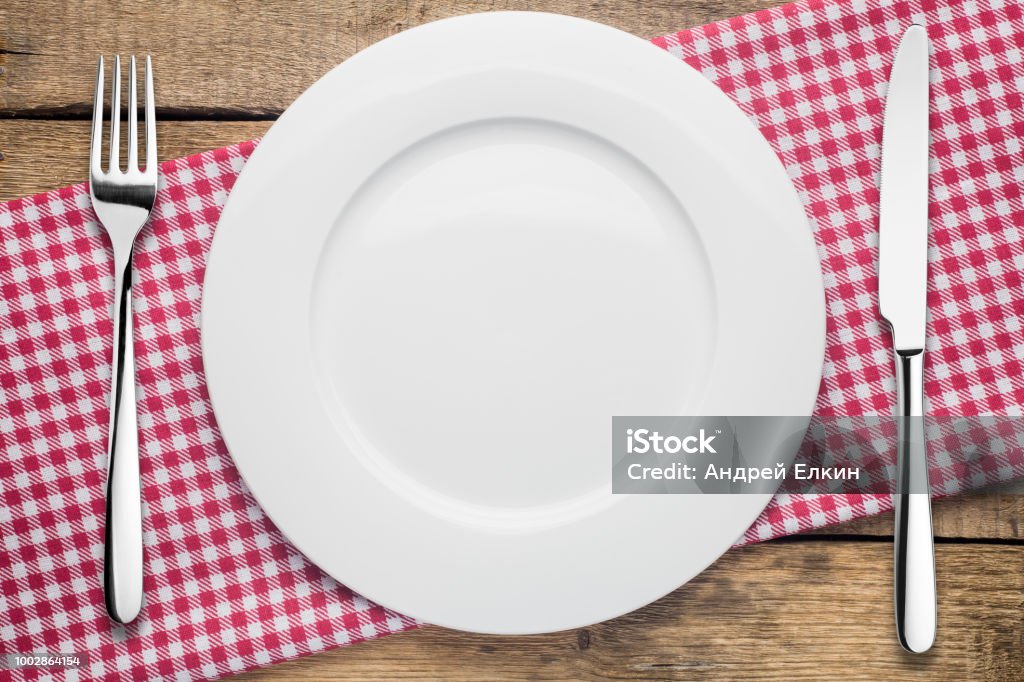 assiette vide sur un fond en bois, une serviette de table en un rouge et blanc - Photo de Assiette libre de droits