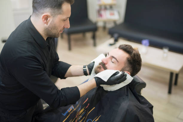 istock Putting an aftershave on his customer's beard 1002864414