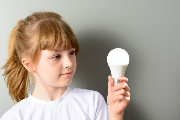 Cute little girl holding a luminous led light bulb stock photo
