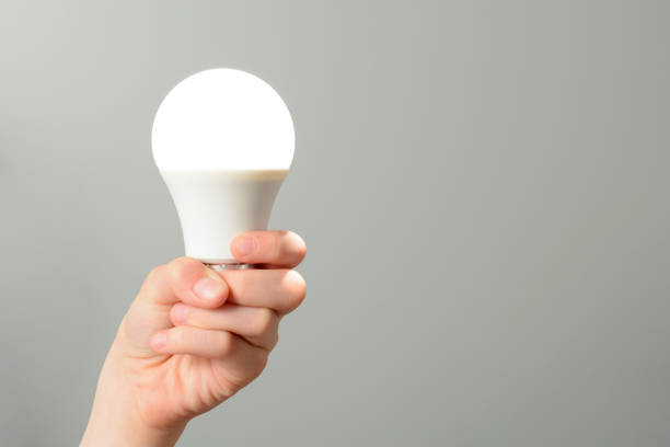 istock Children's hand holds a glowing led bulb 1002864614