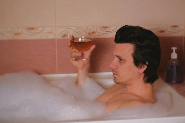istock Man takes a bath and drinks cognac and crying. Depression and problems in life. 1002867440