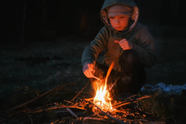 istock Seven-year-old boy light a fire in the woods. 1002869022