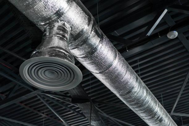 istock Ventilation system on the ceiling of large buildings. Ventilation pipes in silver insulation material hanging from the ceiling inside new building. 1002871932