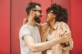 side view of happy young multiethnic couple dancing and holding hands