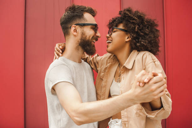 side view of happy young multiethnic couple dancing and holding hands side view of happy young multiethnic couple dancing and holding hands boyfriend stock pictures, royalty-free photos & images