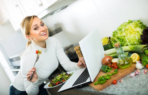 istock Girl eating with laptop in kitchen 1002874664
