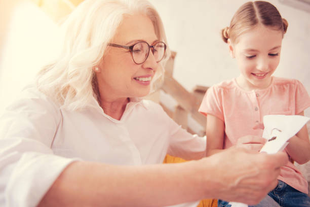 istock Joyful elderly lady embroidering with granddaughter 1002877340