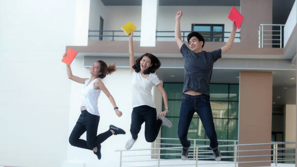 education, school and people concept - Cheerful university students with notebook; Asia university. stock photo