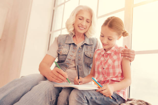 istock Loving granny hugging her granddaughter while both drawing 1002879852