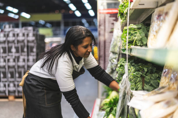 die pflege der verkäuferin mit gemüse im supermarkt - sales clerk store manual worker retail stock-fotos und bilder