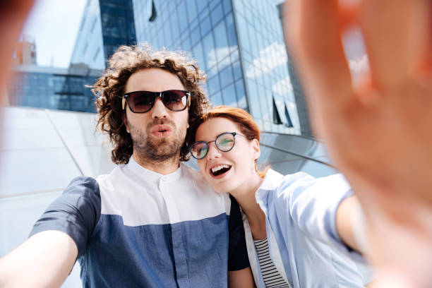 istock Young couple wearing glasses laughing while making selfie 1002885068