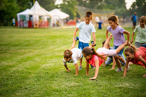 Below view of playful children having fun in wheelbarrow race